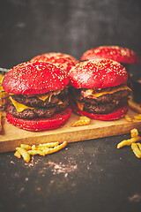 Image showing A set of red bun homemade delicious burgers of beef, bacon, cheese, grilled onion on a dark rusty