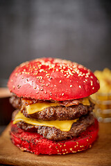 Image showing Homemade red sesame bun double bacon cheese burger. Served with french fries on wooden board.