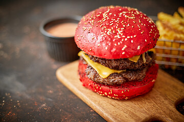 Image showing Homemade red sesame bun double bacon cheese burger. Served with french fries on wooden board.