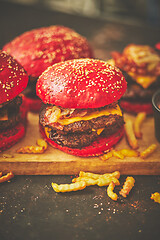 Image showing A set of red bun homemade delicious burgers of beef, bacon, cheese, grilled onion on a dark rusty