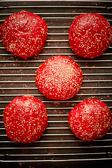 Image showing Fresh baked red homemade burger buns with sesame top view. Placed on metal grill.