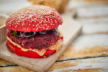 Image showing Homemade vegetable beetroot burgers. Red colored sesame bun. Served with goat cheese, feta