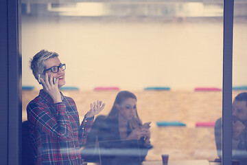 Image showing business woman at office speaking by phone  team on meeting in b