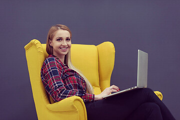 Image showing startup business, woman  working on laptop and sitting on yellow