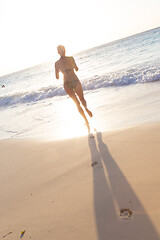 Image showing Woman running on the beach in sunset.