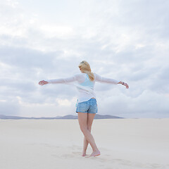 Image showing Carefree woman enjoying freedom on white sand dune at dusk.