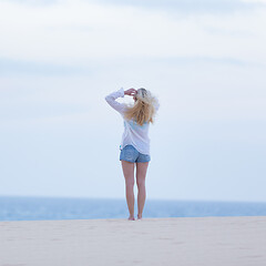 Image showing Woman on sandy beach in white shirt at dusk.