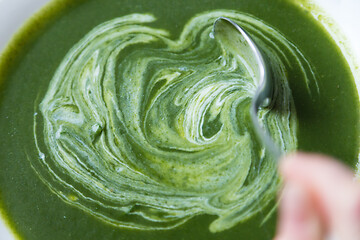 Image showing Creamy spinach soup in plate beeing mixed with spoon