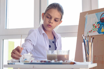 Image showing Girl-artist concentrated wets brush in paint for drawing still life