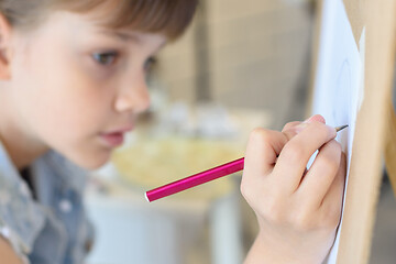 Image showing close-up of the hand of a girl drawing a pencil on an easel