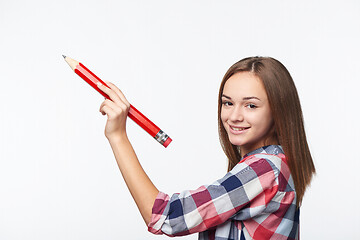 Image showing Smiling teen girl writing with big pencil on blank copy space