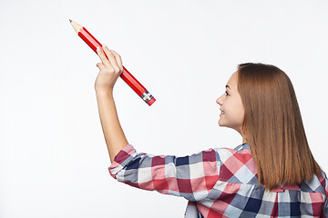 Image showing Profile of a teen girl writing with big pencil on blank copy space