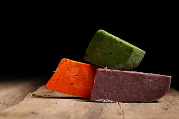 Image showing Three different gourmet cheeses on rough woode planks