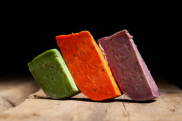 Image showing Three different gourmet cheeses on rough woode planks