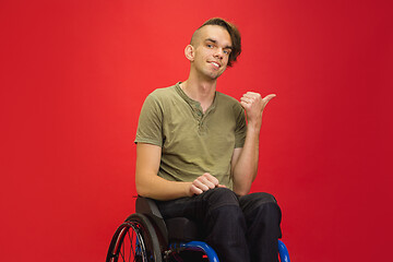 Image showing Caucasian young man\'s portrait isolated on red studio background. Human emotions concept