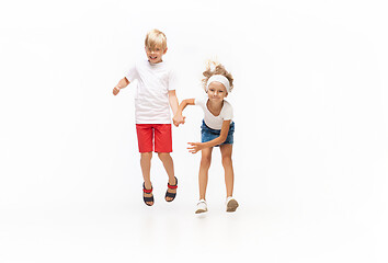 Image showing Happy little caucasian girl and boy jumping and running isolated on white background