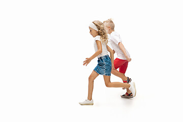 Image showing Happy little caucasian girl and boy jumping and running isolated on white background