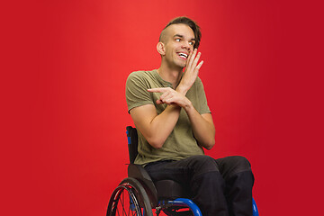 Image showing Caucasian young man\'s portrait isolated on red studio background. Human emotions concept