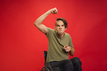 Image showing Caucasian young man\'s portrait isolated on red studio background. Human emotions concept