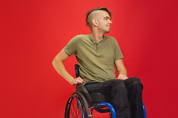 Image showing Caucasian young man\'s portrait isolated on red studio background. Human emotions concept