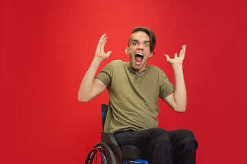 Image showing Caucasian young man\'s portrait isolated on red studio background. Human emotions concept