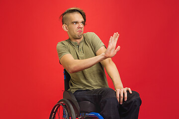 Image showing Caucasian young man\'s portrait isolated on red studio background. Human emotions concept