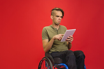 Image showing Caucasian young man\'s portrait isolated on red studio background. Human emotions concept