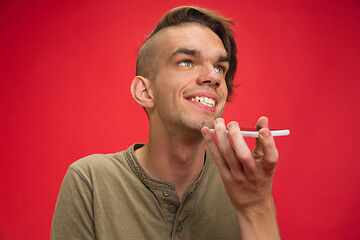 Image showing Caucasian young man\'s portrait isolated on red studio background. Human emotions concept