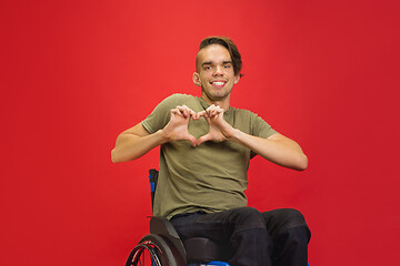 Image showing Caucasian young man\'s portrait isolated on red studio background. Human emotions concept