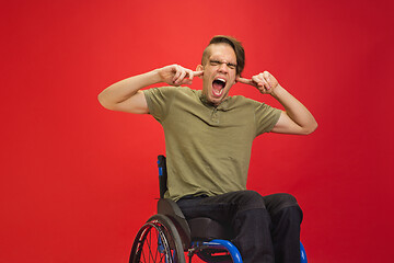 Image showing Caucasian young man\'s portrait isolated on red studio background. Human emotions concept