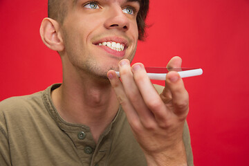 Image showing Caucasian young man\'s portrait isolated on red studio background. Human emotions concept