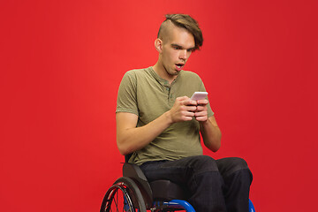 Image showing Caucasian young man\'s portrait isolated on red studio background. Human emotions concept