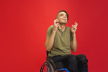 Image showing Caucasian young man\'s portrait isolated on red studio background. Human emotions concept