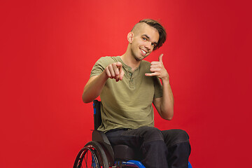 Image showing Caucasian young man\'s portrait isolated on red studio background. Human emotions concept