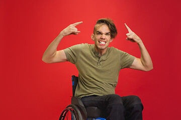 Image showing Caucasian young man\'s portrait isolated on red studio background. Human emotions concept