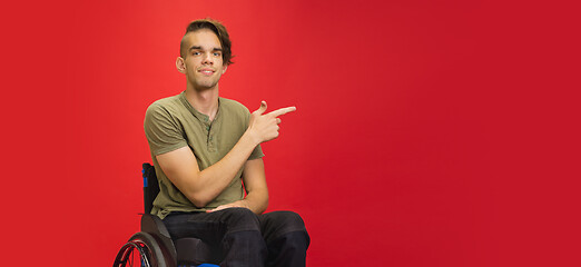 Image showing Caucasian young man\'s portrait isolated on red studio background. Human emotions concept