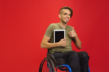 Image showing Caucasian young man\'s portrait isolated on red studio background. Human emotions concept