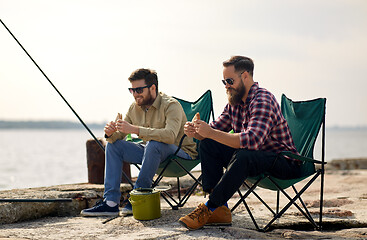 Image showing happy friends fishing and eating sandwiches