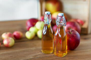 Image showing bottles of apple juice or vinegar on wooden table