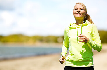 Image showing smiling woman running along beach