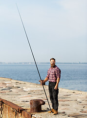 Image showing bearded fisherman with fishing rod on sea pier