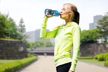 Image showing woman drinking water after exercising in city park