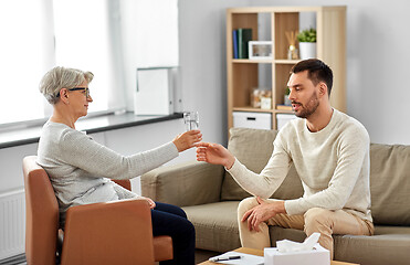 Image showing senior psychologist giving water to man patient