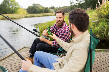 Image showing happy friends fishing and drinking beer on pier