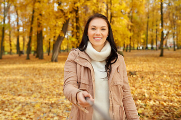 Image showing woman taking picture by selfiestick at autumn park