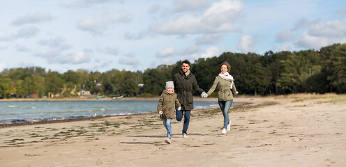 Image showing happy family running along autumn beach