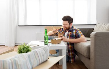 Image showing smiling man eating takeaway food at new home