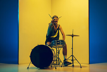 Image showing Young caucasian musician inspired performing on yellow background in neon light