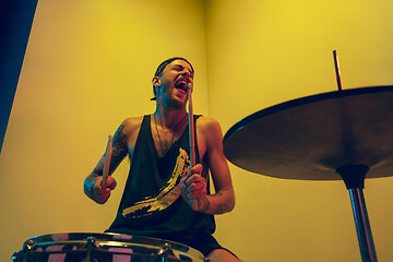 Image showing Young caucasian musician inspired performing on yellow background in neon light