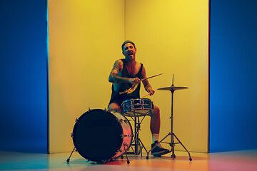 Image showing Young caucasian musician inspired performing on yellow background in neon light